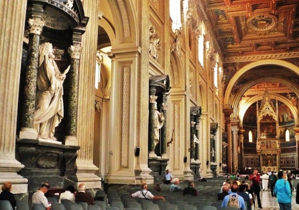 Archbasilica of St John Lateran (San Giovanni in Laterano), part of the nave with statues of the twelve apostles, in front of the baldacchino (canopy) over the altar containing the heads of Sts Peter and Paul. The papal cathedra is in the apse beyond.